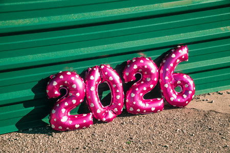 the number 2026, like the new year, appears in shiny pink balloons decorated with white hearts,...