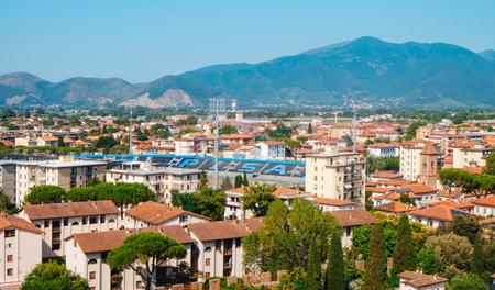 Pisa, Italy - June 26, 2025: Aerial view over Pisa with the Arena Garibaldi stadium stands visible among residential buildings, red tiled roofs, green trees, and the mountains rising in the distanceのeditorial素材