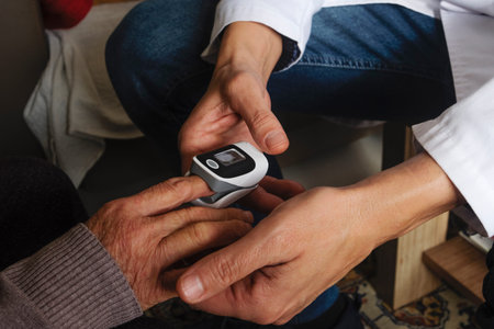 a healthcare worker places a pulse oximeter on the finger of an elderly woman seated at home,...