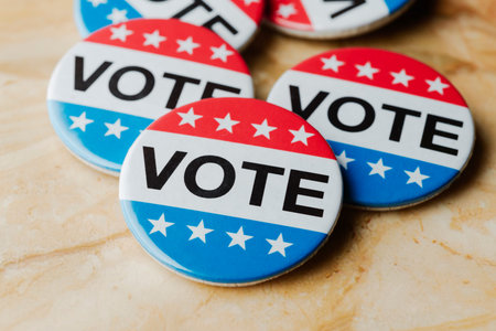 close view of several red, white, and blue vote badges grouped on a marble background, political election symbol encouraging citizens to participate and vote