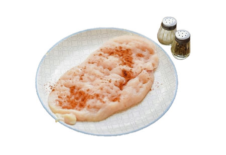 Rinse and dry the chicken fillet, cut the fillet in half. Cover the fillet with cling film, beat with a kitchen hammer. Sprinkle the fillets with salt, pepper and paprika.の写真素材