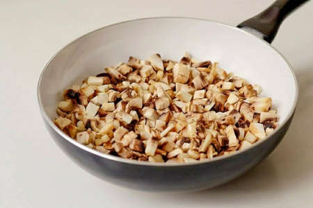 Add the diced mushrooms. Fry them until the excess liquid evaporates.の写真素材