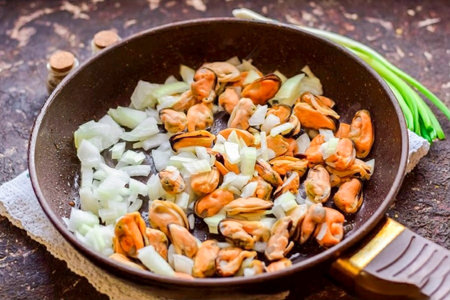 Heat a frying pan with vegetable oil, transfer the onion and mussels.の写真素材
