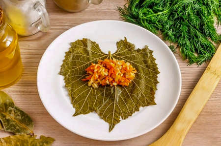 Arrange the pickled or pickled grape leaf on a board or plate, removing the stalk. Put 1.5 tsp on it. cooked minced meat. The smaller the cooked sarmale is, the more they are appreciated. The ideal size is the size of the little finger.の写真素材