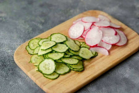 Cut the cucumber and radish into thin slices.の写真素材