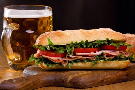 sandwich with bacon and vegetables with mug of beerの写真素材