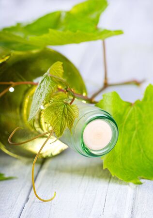 bottle of wine with leaves on wooden tableの写真素材