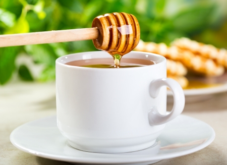 pouring honey into cup of teaの写真素材