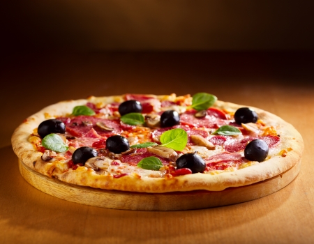 pizza with salami and bacon on wooden tableの写真素材
