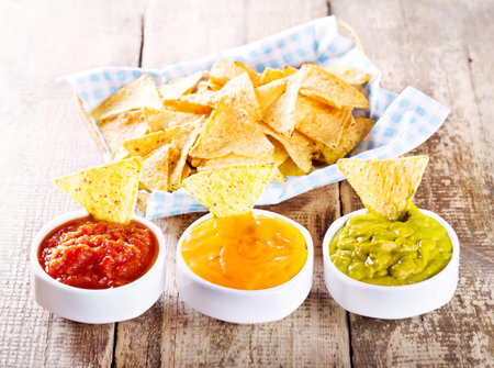 nachos with various sauces on wooden table