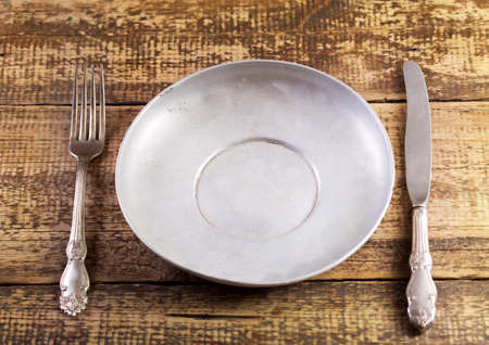 empty plate fork and knife on wooden tableの写真素材