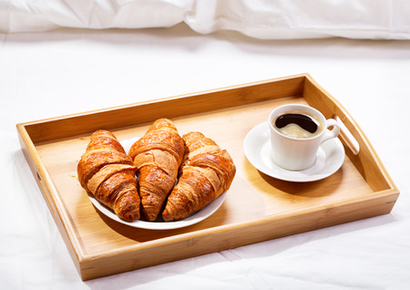 breakfast in bed with coffee and croissantsの写真素材