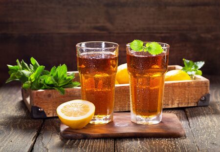 glasses of ice tea with mint and lemon on wooden tableの写真素材