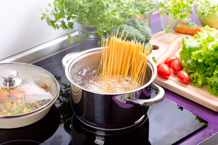 pan of boiling water with spaghetti on the cooker in the kitchenの写真素材