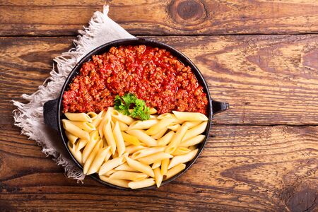 pasta bolognese in a pan on wooden tableの写真素材