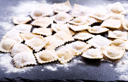 Raw ravioli with flour on dark boardの写真素材