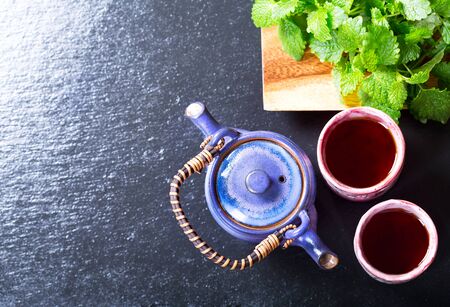Teapot and cups of tea with mint on dark background, top viewの写真素材