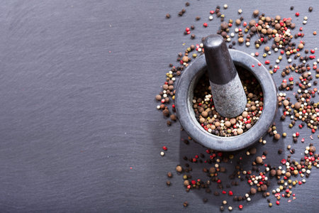 Mixed pepper in mortar on dark background