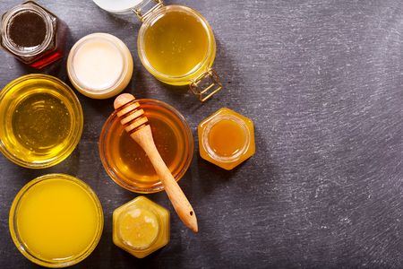 various types of honey in glass jars on a dark tableの写真素材