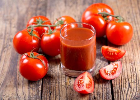 glass of tomato juice with fresh tomatoes on wooden tableの写真素材