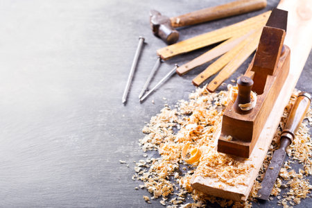 old tools: wooden planer, hammer, chisel  in a carpentry workshop on dark background