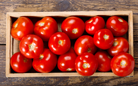 fresh tomatoes in a box on wooden table, top viewの写真素材