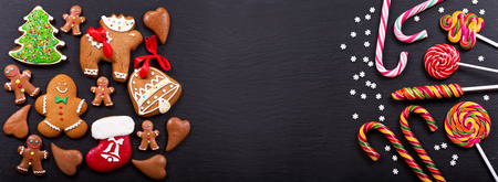 Christmas homemade gingerbread cookies and colorful lollipops on dark table, top viewの写真素材