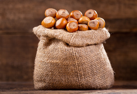 hazelnut in a sack on a wooden tableの写真素材