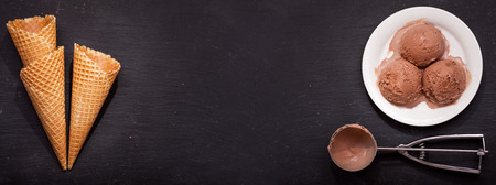 plate of chocolate ice cream scoops and waffle cones  on dark background, top viewの写真素材