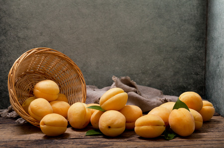 fresh apricots in a basket on wooden tableの写真素材