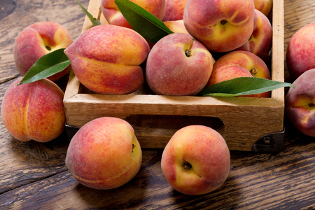 fresh peaches with leaves in a wooden boxの写真素材