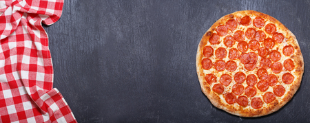 Pizza pepperoni on dark background, top viewの写真素材