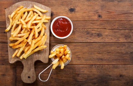 French fries with ketchup on wooden board