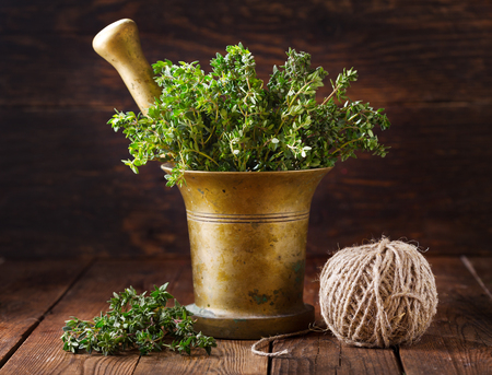 bunch of fresh green thyme in a mortar on wooden tableの写真素材