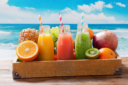 bottles of fruit juice and smoothie with fresh fruits in wooden boxの写真素材