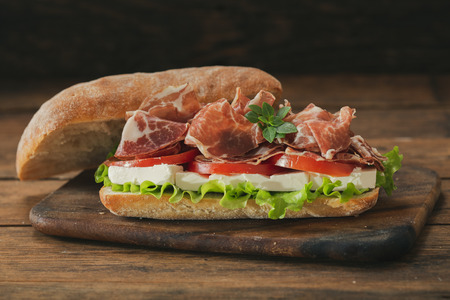 sandwich with ham and vegetables on wooden tableの写真素材