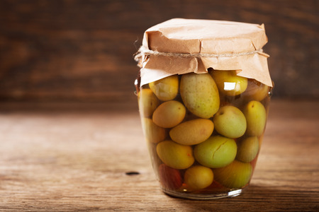 glass jar of pickled olives on wooden tableの写真素材