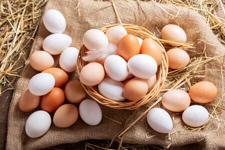 basket of colorful fresh eggs on wooden table, top viewの写真素材