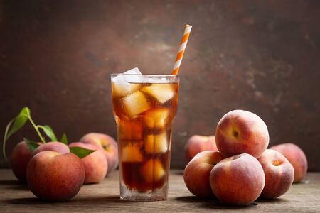 glass of peach iced tea with fresh fruits on wooden tableの写真素材