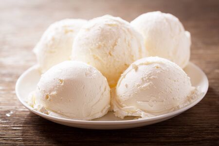 plate of ice cream scoops on a wooden tableの写真素材