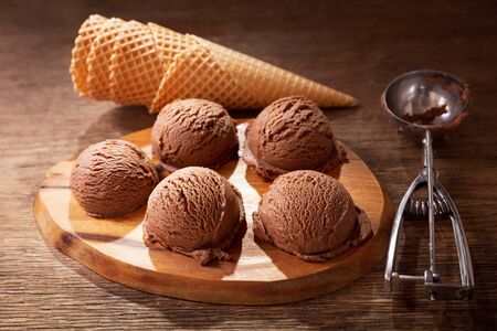 chocolate ice cream scoops with waffle cones on a wooden boardの写真素材