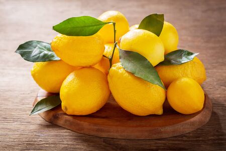Fresh lemons with leaves on a wooden tableの写真素材