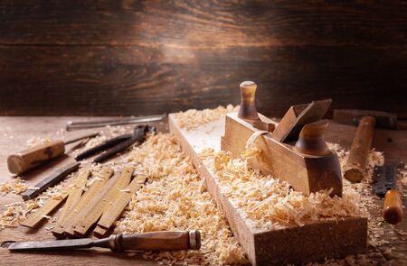 old tools: wooden plane, hammer, chisel in a carpentry workshop on wooden tableの写真素材