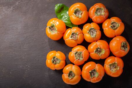 fresh ripe persimmon fruit on a dark background, top viewの写真素材