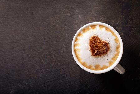 Valentines day.  Cup of cappuccino coffee with drawn heart on dark background, top viewの写真素材
