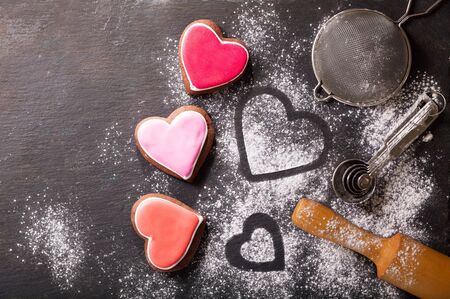 Baking for Valentines Day. Colorful Heart shapped cookies and kitchen utensils on dark background, top viewの写真素材