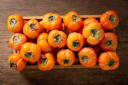 fresh ripe persimmon fruit in a wooden box, top viewの写真素材