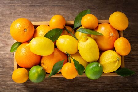 Mix of fresh fruits with leaves in a wooden box, top viewの写真素材