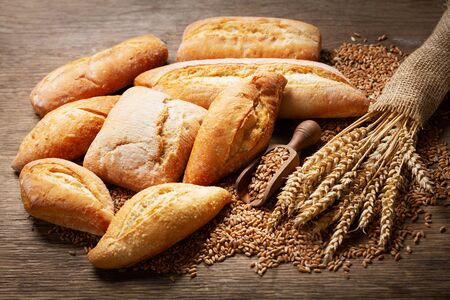 fresh bread with wheat ears and grains on a wooden tableの写真素材