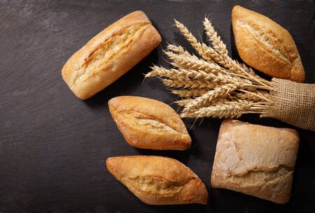fresh bread with wheat ears on a dark background, top viewの写真素材